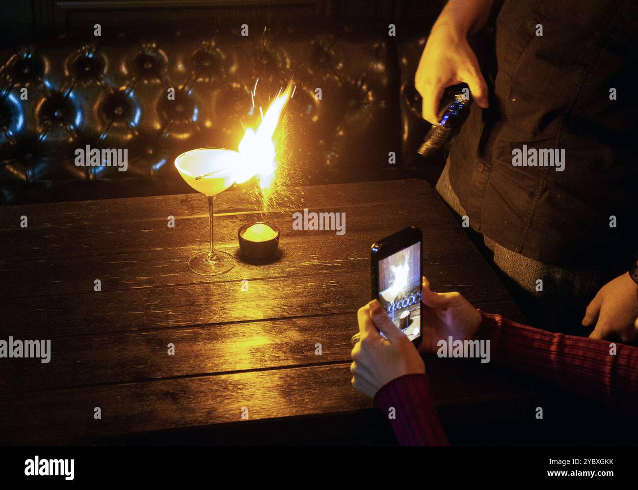 Dans le restaurant prendre la vidéo (bobines pour le réseau social pour la publicité) sur smartphone - une autre personne fait une action pour préparer un cocktail avec le « feu » Banque D'Images