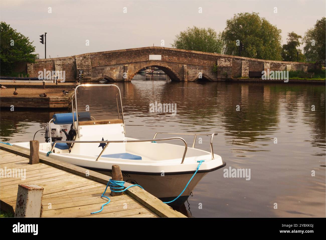 Une vue sur le pont Potter Heigham et la marina sur la rivière Thurne, avec un petit bateau de croisière le long du poste d'amarrage. Norfolk Broads, Angleterre, Royaume-Uni Banque D'Images