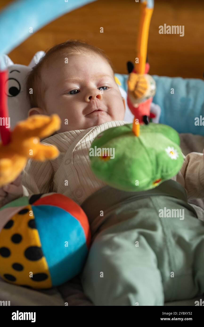 Petite fille explorant des jouets colorés dans un cadre ludique, captivée et curieuse Banque D'Images