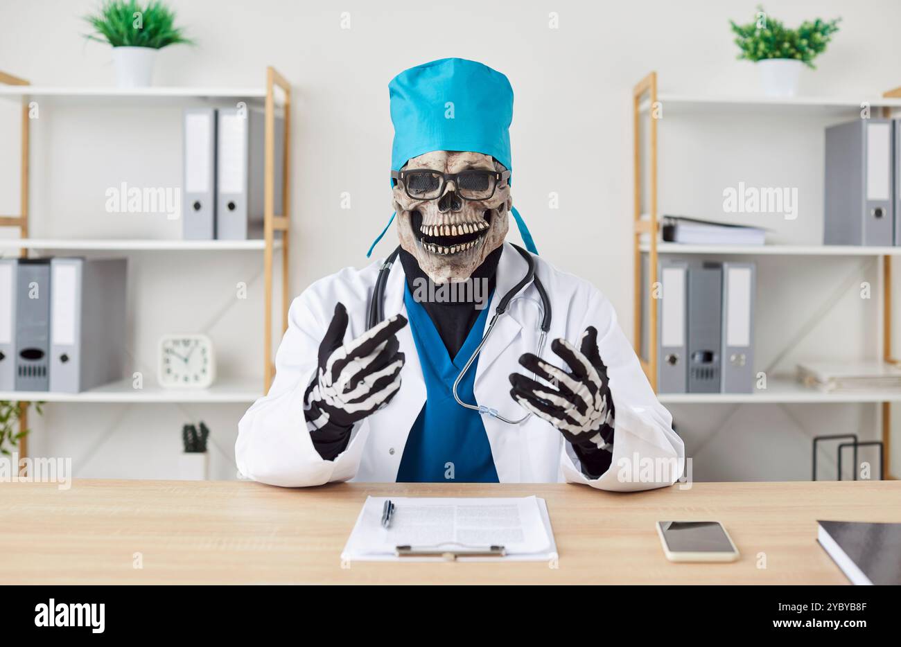 Médecin masculin mort dans le masque squelette de scull assis au bureau sur le lieu de travail dans la clinique médicale. Banque D'Images