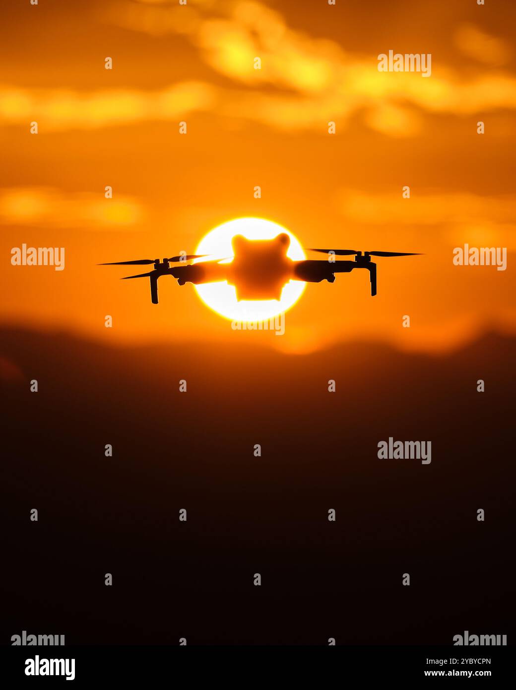 gros plan d'un drone volant vers le soleil en arrière-plan approchant les montagnes pour commencer le coucher de soleil, photo avec des couleurs oranges Banque D'Images