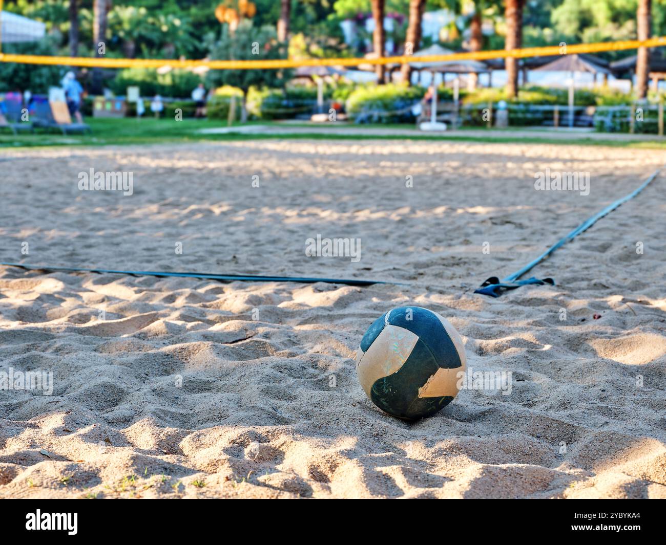 Concept de Beach volley. Le volley usé repose sur un terrain de plage de sable, se prélasser dans la lumière du soleil d'été, évoquant les loisirs et les loisirs. Ce moi vibrant Banque D'Images
