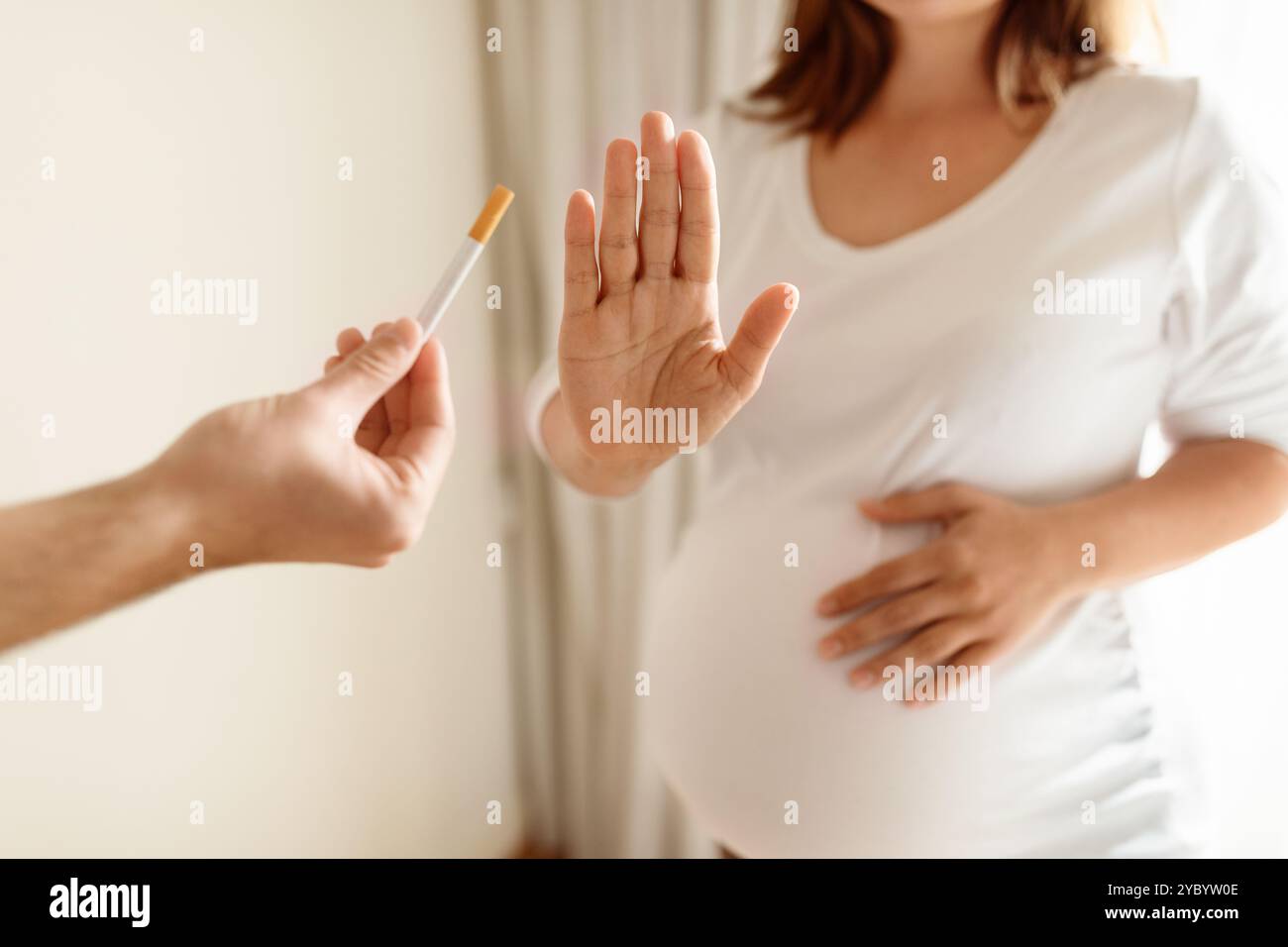 Femme enceinte refusant une cigarette dans un cadre intérieur lumineux pendant la journée Banque D'Images