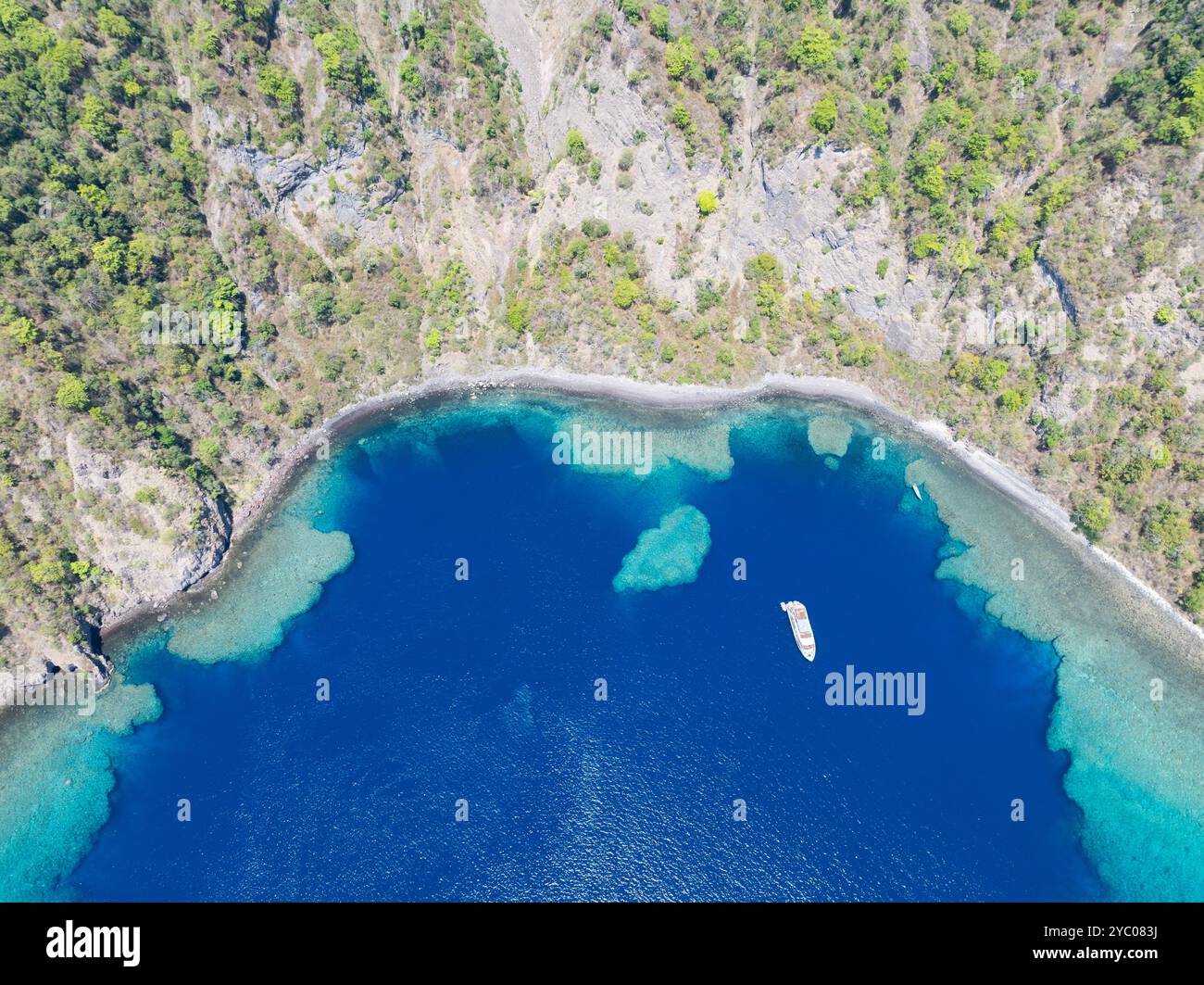 Entourée de récifs coralliens, la côte reculée et accidentée de l'île volcanique de Komba se trouve à 70 km au nord des petites îles Sunda d'Indonésie. Banque D'Images