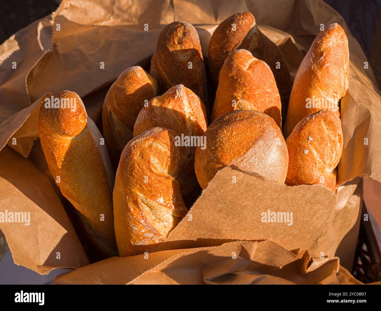 Tôt le matin, la lumière brille sur les baguettes françaises fraîchement préparées sur un marché local en plein air Banque D'Images