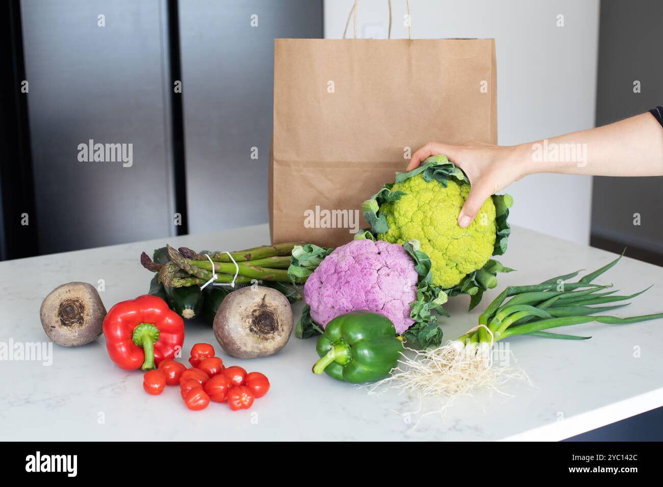 La main de la femme prend le chou-fleur des légumes sur la table de cuisine Banque D'Images