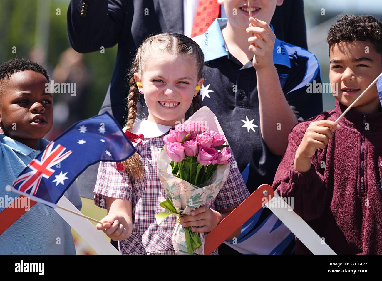 Les écoliers brandissent les drapeaux australiens en attendant l'arrivée du roi Charles III et de l'aéroport Queen Camilla ay Canberra, le deuxième jour de leur visite en Australie et aux Samoa. Date de la photo : lundi 21 octobre 2024. Banque D'Images