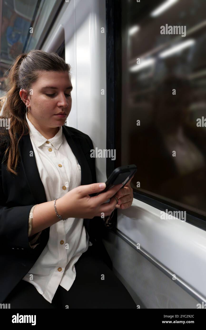 Jeune femme d'affaires dans un costume travaillant sur smartphone pendant le voyage de nuit en train Banque D'Images