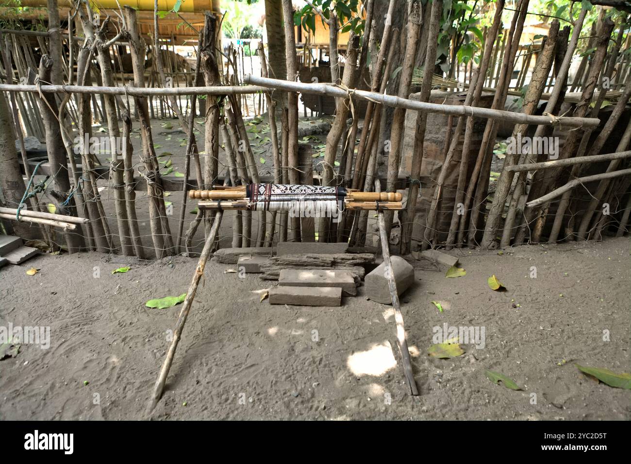 Un rouleau d'ensemble de tissage est appuyé contre une clôture en bois dans le village traditionnel d'Umabara à Umalulu, Sumba est, Nusa Tenggara est, Indonésie. Banque D'Images