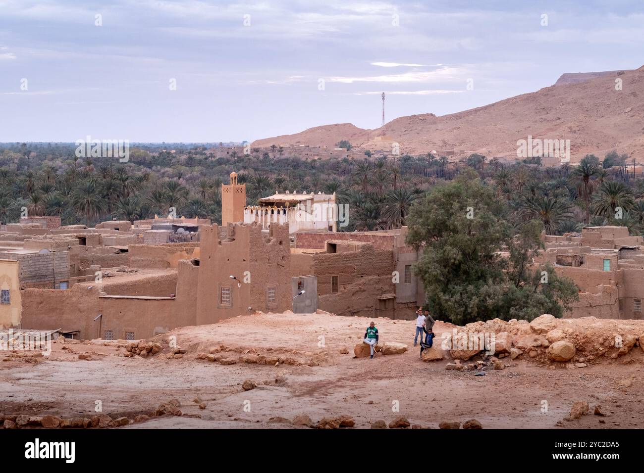Certains enfants saluent la caméra dans une petite ville avec une mosquée dans l'immense oasis de Tafilalet au Maroc, en Afrique du Nord. Rivière Ziz au milieu de la d Banque D'Images