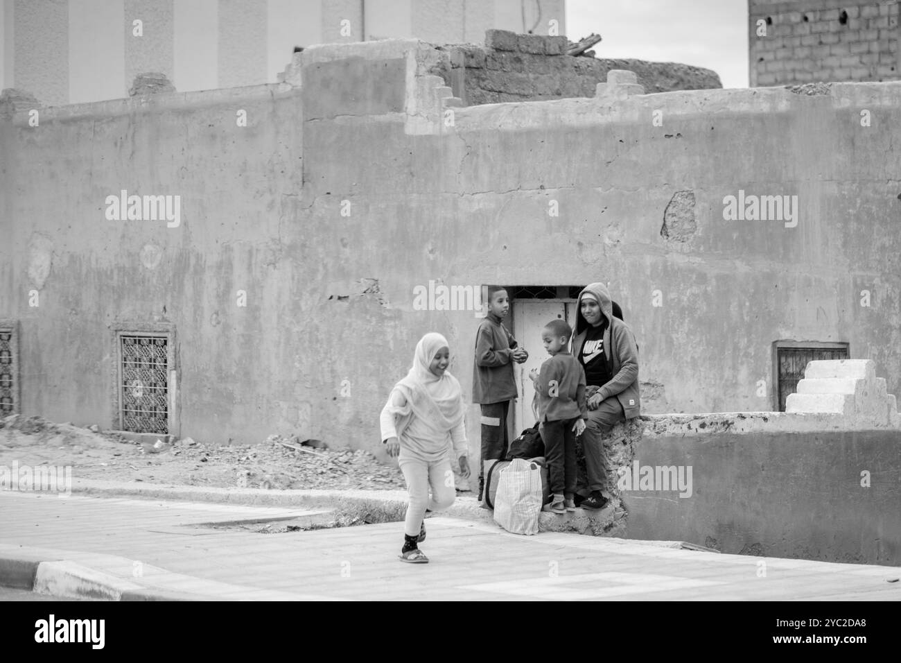 Photo en noir et blanc d'un homme plus âgé roule calmement et souriant à l'arrière d'un petit véhicule de type scooter à trois roues. C'est un quotidien typique Banque D'Images