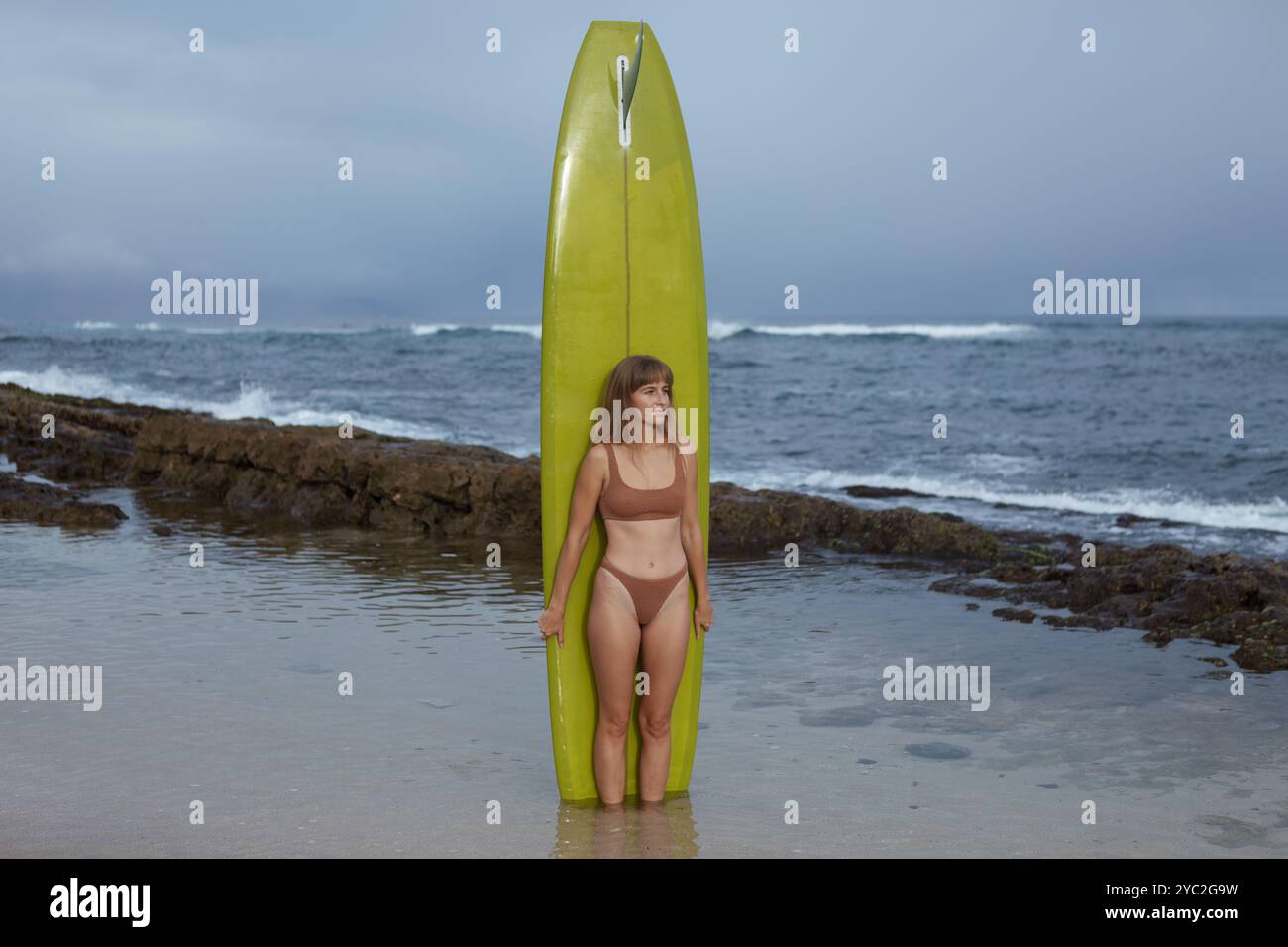 femme debout avec planche de surf dans tidepool Banque D'Images