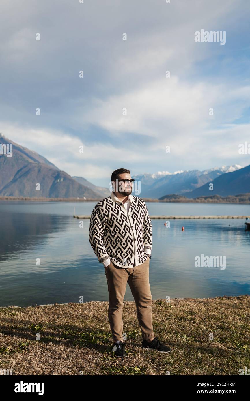 Jeune homme élégant debout devant les montagnes et le lac Banque D'Images