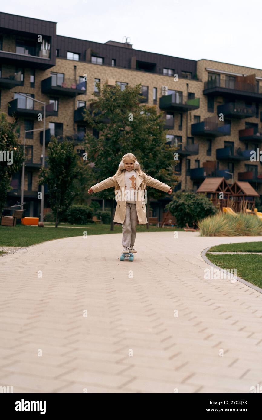 Fille heureuse poussant sur le skateboard dans la rue Banque D'Images