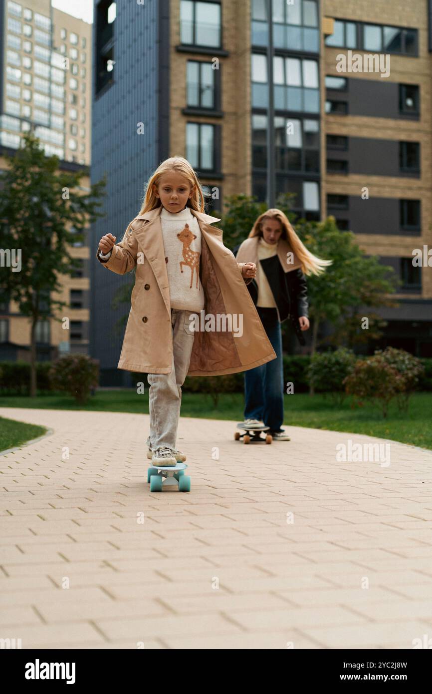 Maman apprend à sa fille à skateboard dans un parc de la ville Banque D'Images