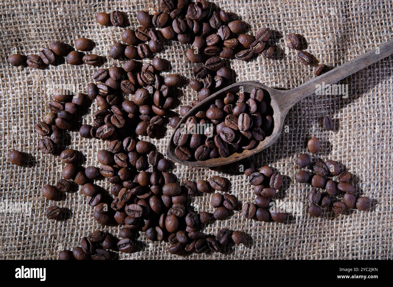 grains de café dans une cuillère en bois sur fond de tissu de sac Banque D'Images