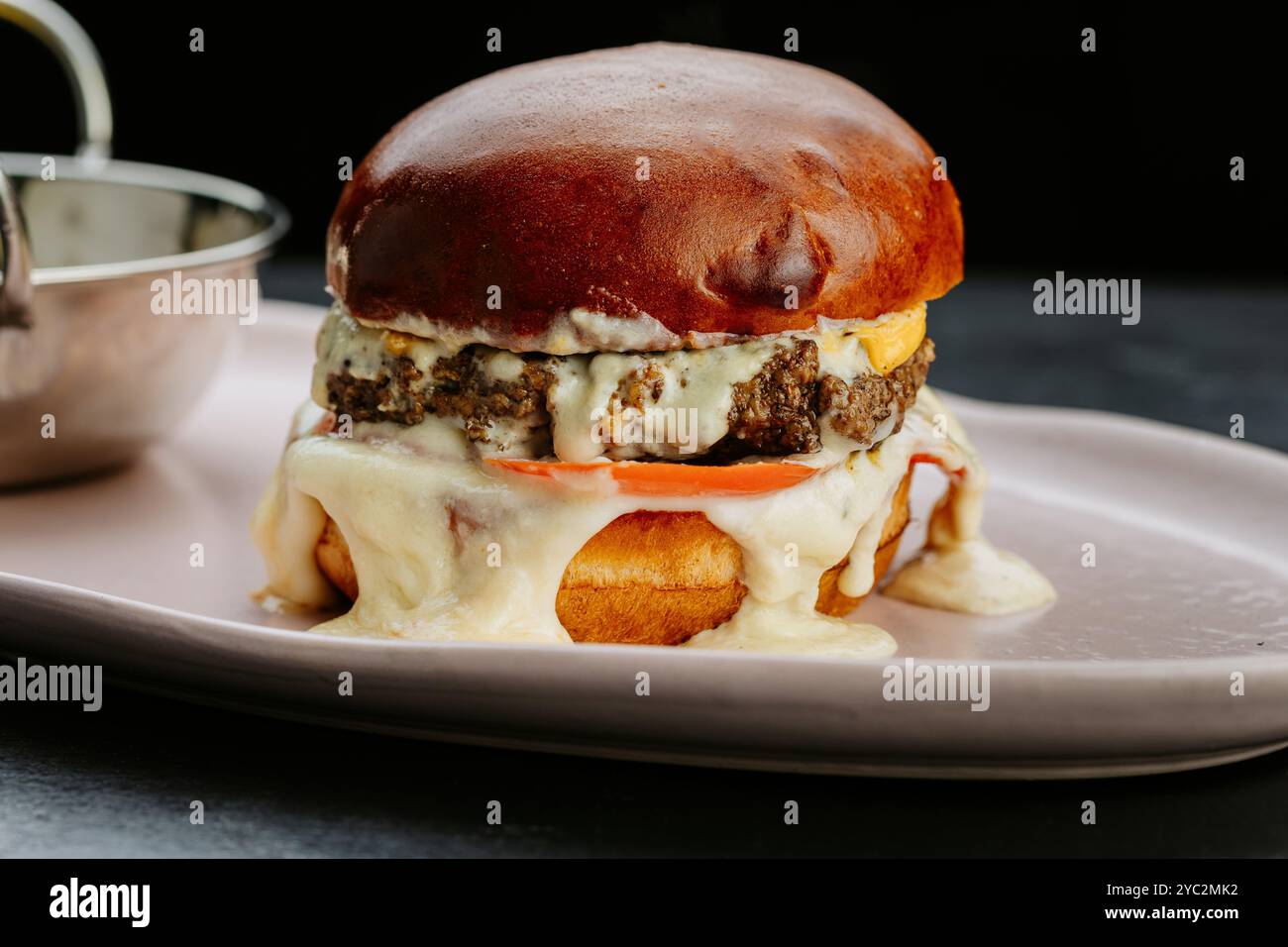 Hamburger juteux avec fromage fondu, tomate et sauce crémeuse pour une expérience culinaire ultime Banque D'Images