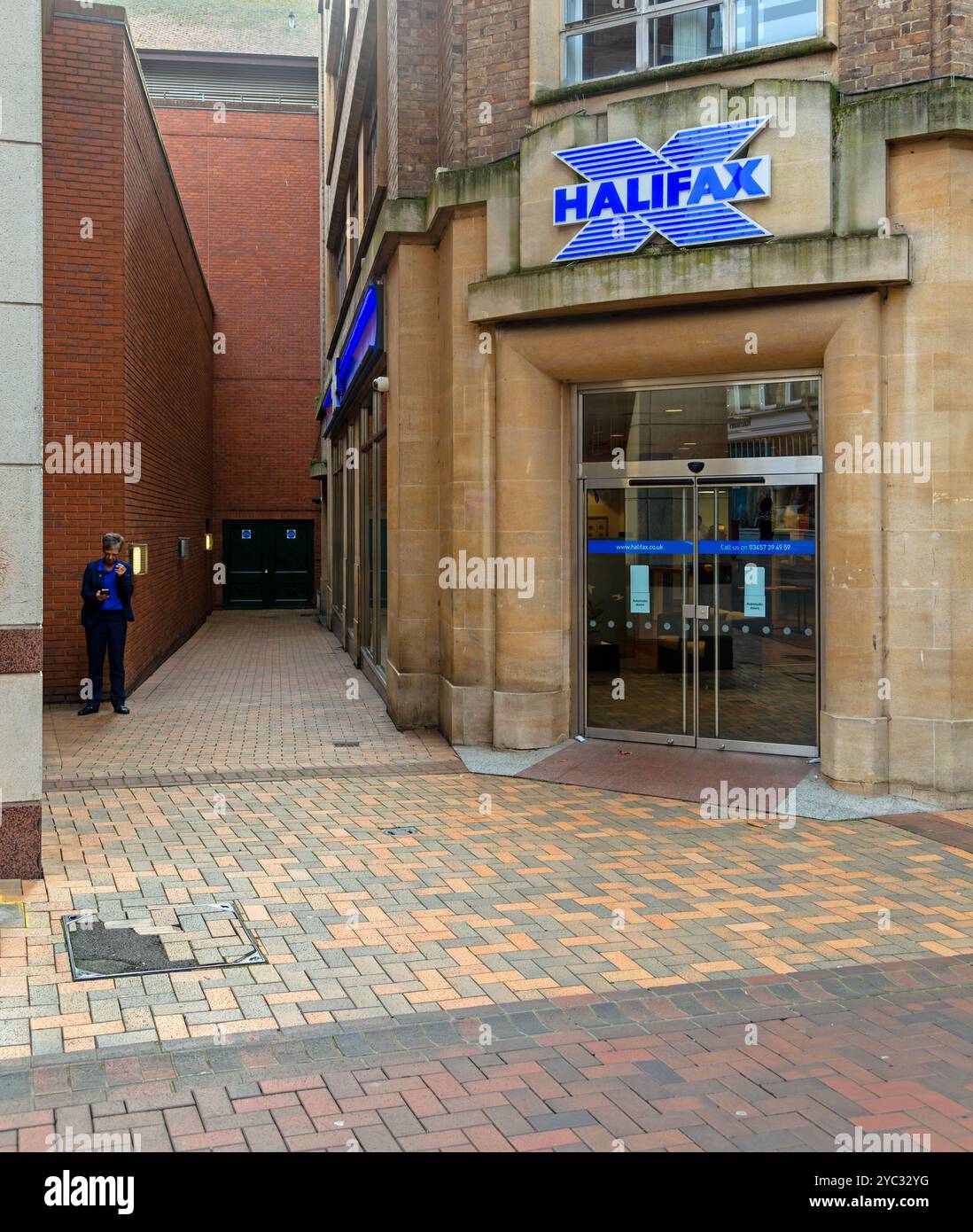 Femme ayant une pause cigarette dans une ruelle à côté de la banque Halifax, Ipswich, Suffolk, Angleterre, Royaume-Uni Banque D'Images