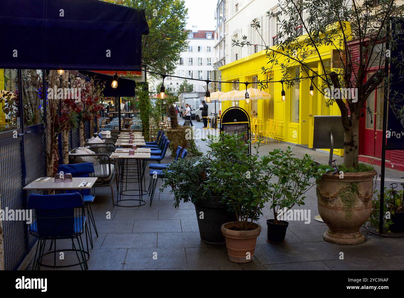 Un patio extérieur vide devant un restaurant parisien. Façade jaune. Rue parisienne calme Banque D'Images Un patio extérieur vide devant un restaurant parisien. Façade jaune. Rue parisienne calme Banque D'Images
