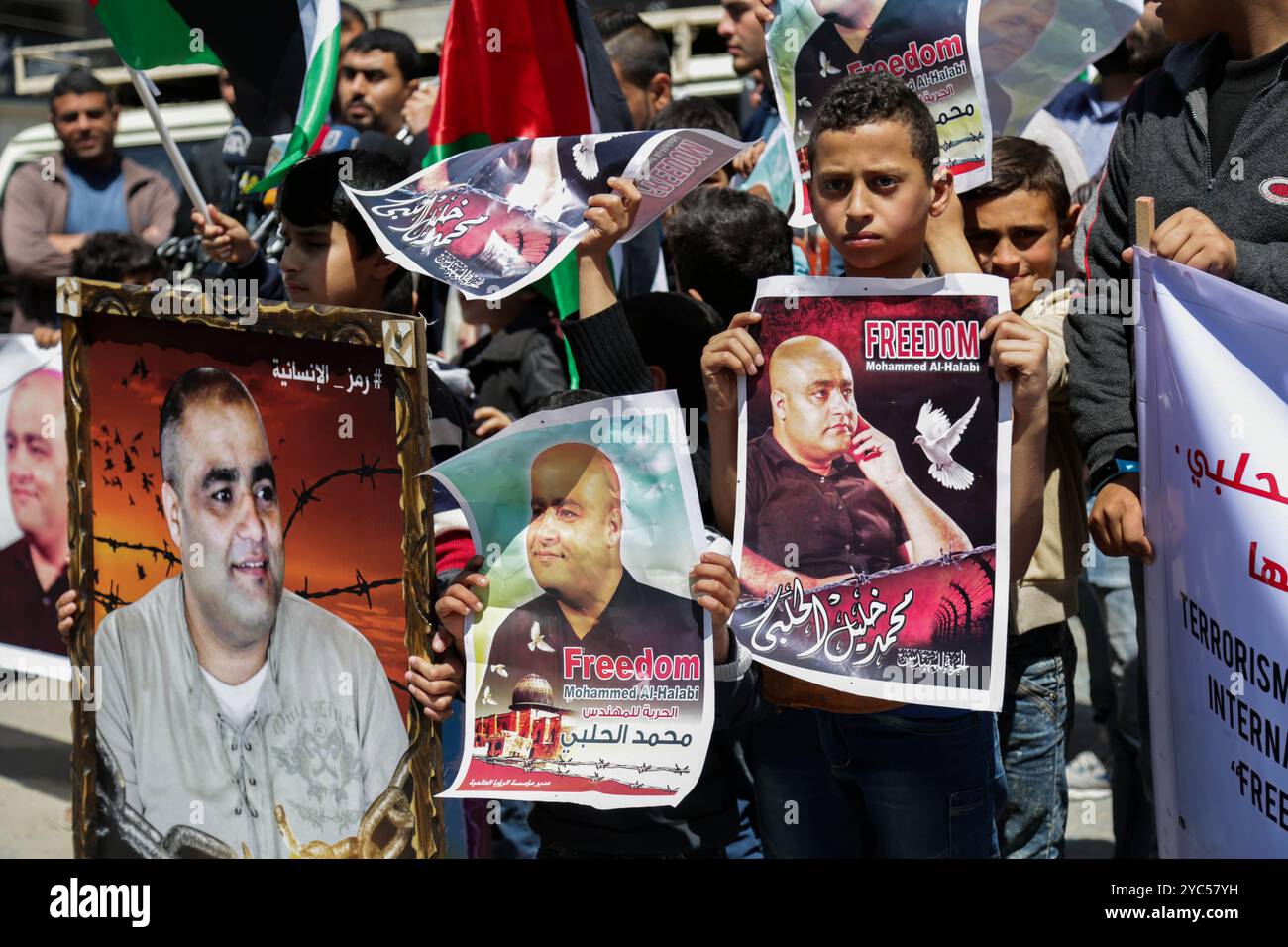 Des Palestiniens, y compris des enfants, se rassemblent et portent des affiches de solidarité avec Mohammed al-Halabi, le directeur des opérations de Global Vision dans la ville de Gaza. Mohammed al-Halabi a été arrêté par les autorités israéliennes le 15 juin 2016 et fait face à plusieurs chefs d’accusation, notamment être membre d’une « organisation terroriste » et siphonner les fonds caritatifs et #8217 pour fournir une aide financière à la branche armée du Hamas des Brigades Izz al-DIN al-Qassam. Amnesty International a exprimé de sérieuses préoccupations au sujet des condamnations prononcées contre M. Al-Halabi &#8217, ainsi que du déroulement de son procès à huis clos, Banque D'Images