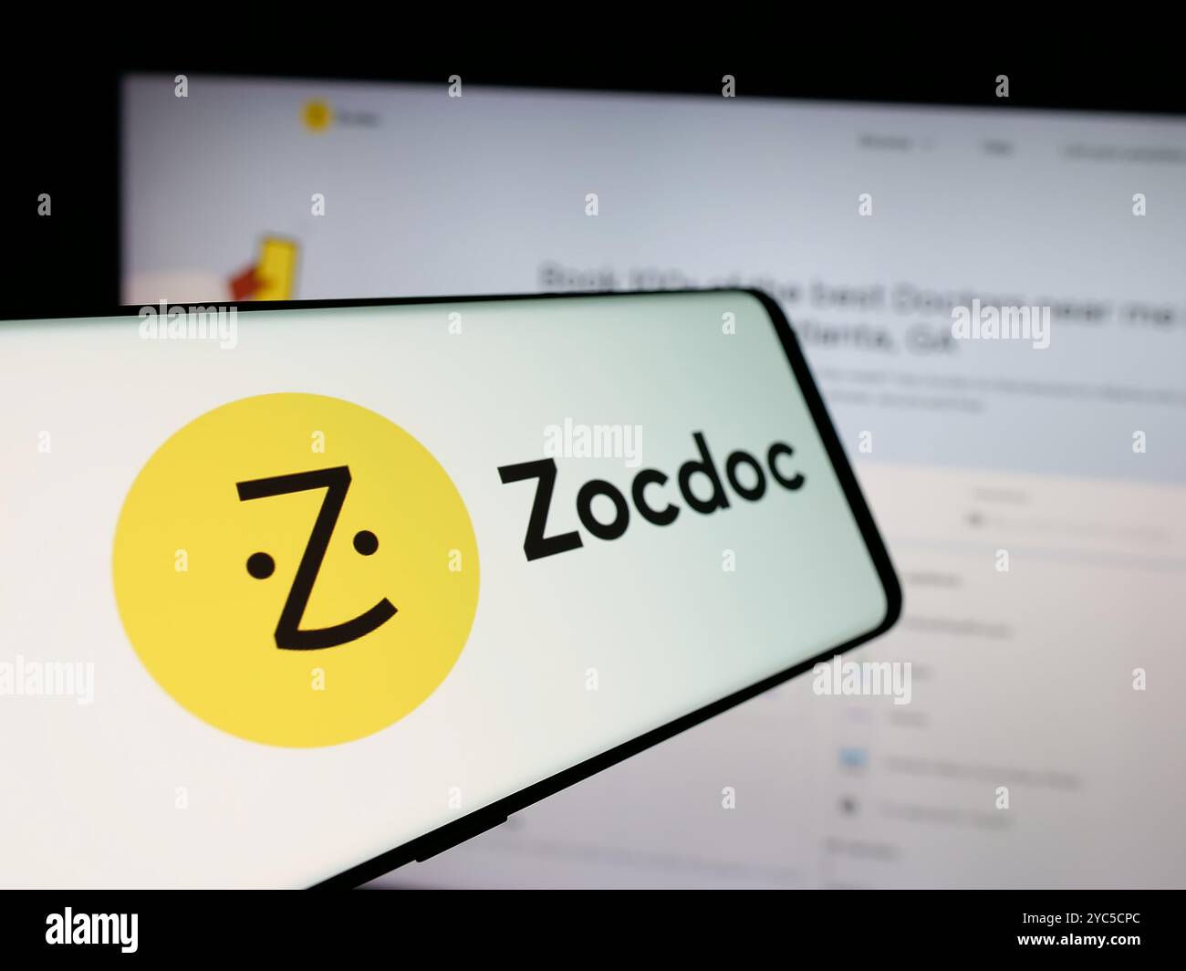 Smartphone avec le logo de la société américaine de télémédecine Zocdoc Inc. sur l'écran en face du site Web de l'entreprise. Mettez l'accent sur le centre-gauche de l'écran du téléphone. Banque D'Images