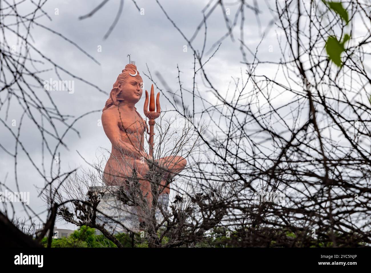 Statue isolée du Seigneur Hindou Shiva dans la posture de méditation avec le ciel dramatique d'une perspective unique Banque D'Images