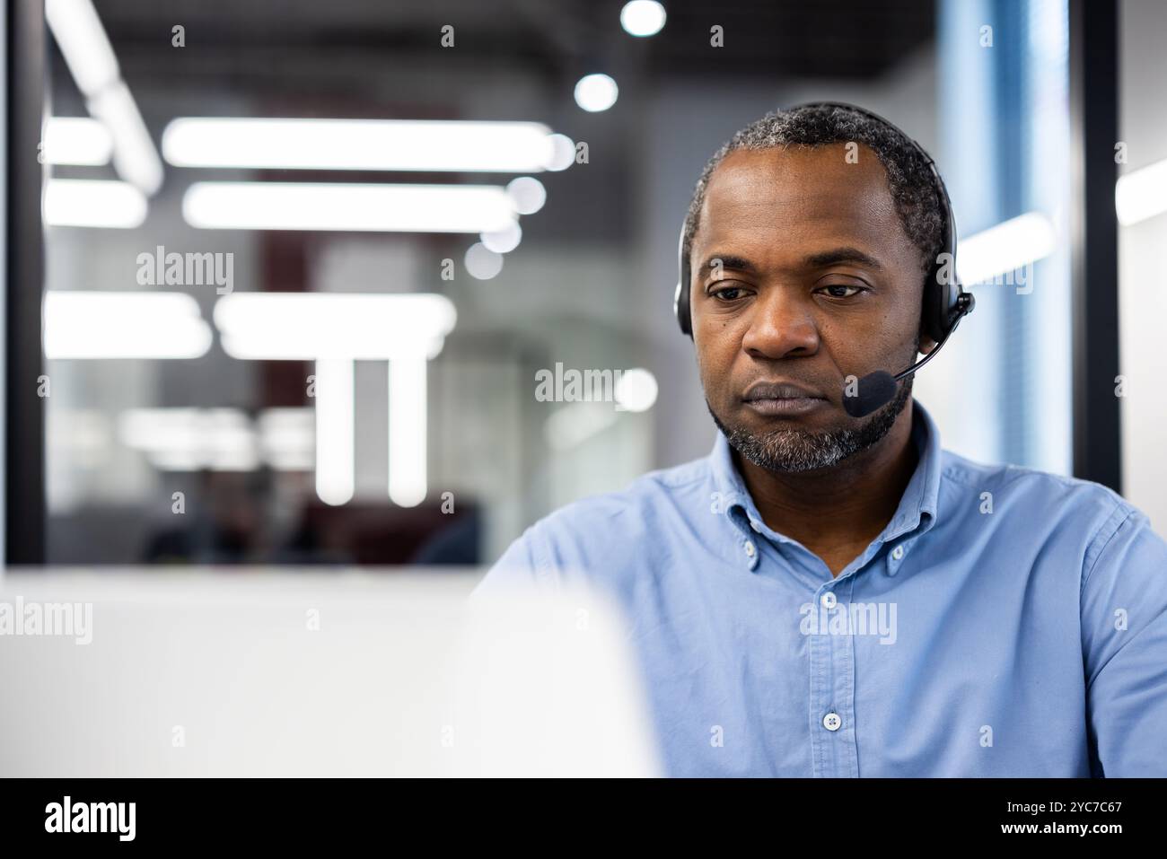 Homme d'affaires mature utilisant un casque dans un environnement de bureau moderne. Concentré sur le travail, engagé dans la réunion virtuelle, reflétant le professionnalisme, la concentration. COR Banque D'Images