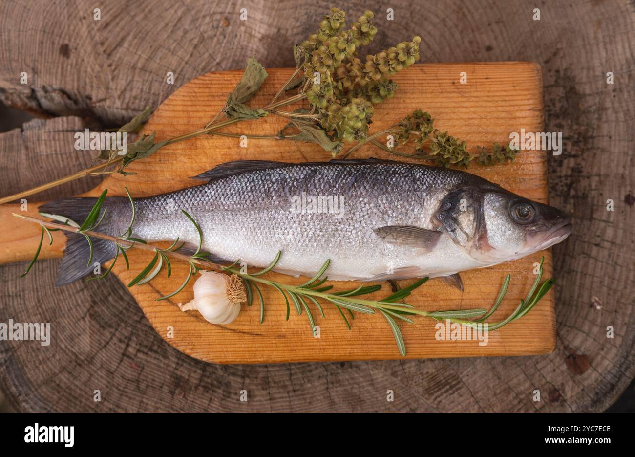 Poisson de bar cru sur table en bois avec décoration d'herbes et d'épices Banque D'Images