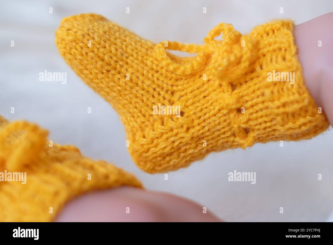 Ces confortables chaussons tricotés jaunes à motif tissé apportent chaleur et charme. Les cravates de laçage en font un accessoire adorable pour la tenue d'un petit Banque D'Images