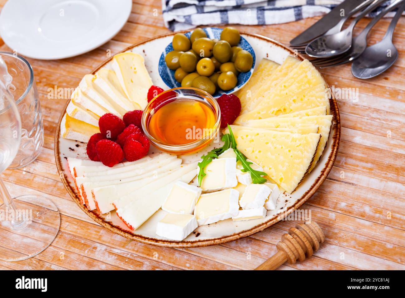 Différents types de fromage, miel, framboises et olives sur bois Banque D'Images