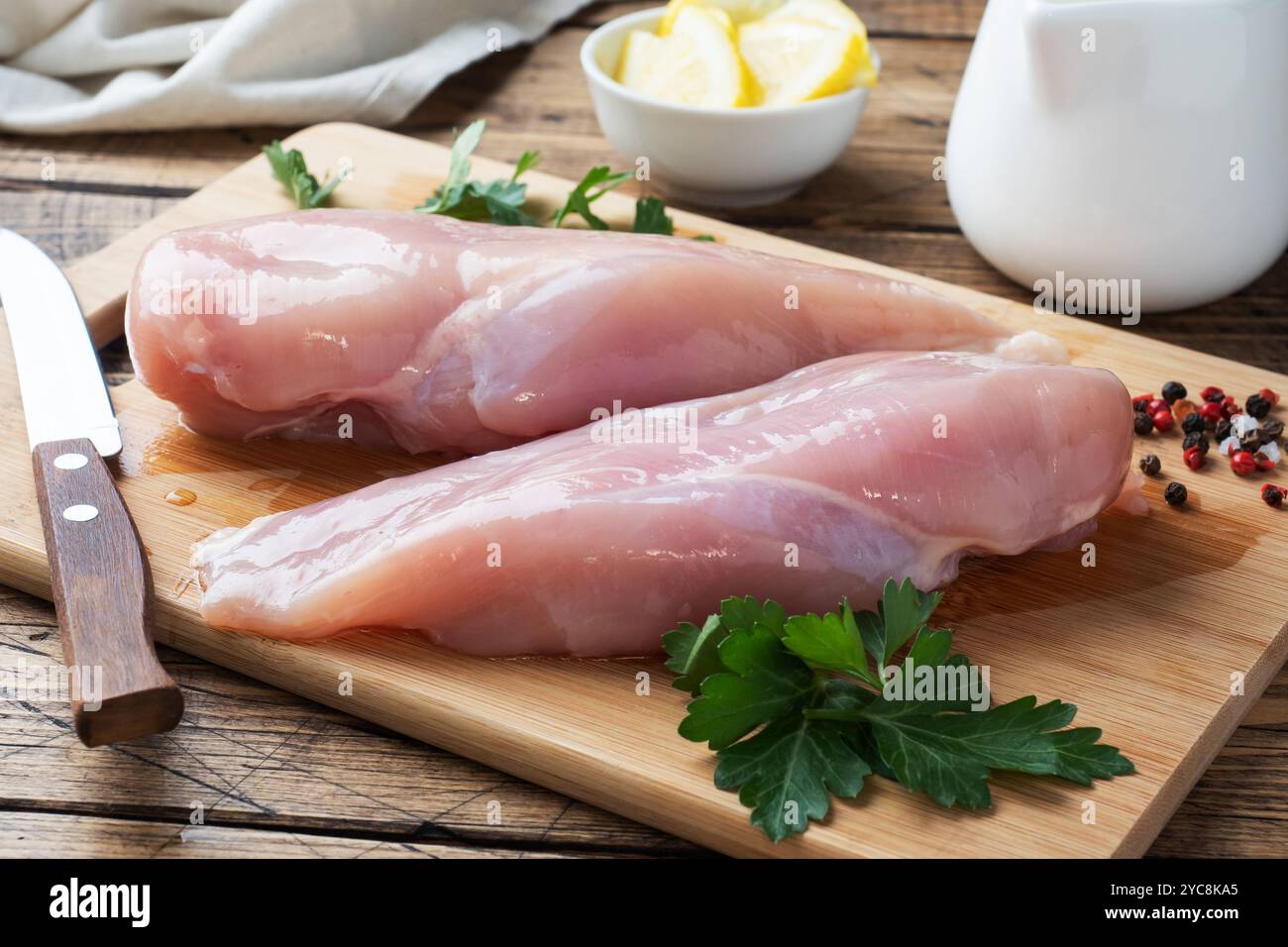 Filet de poitrine de poulet cru sur une planche à découper en bois. Arrière-plan rustique en bois Banque D'Images Filet de poitrine de poulet cru sur une planche à découper en bois. Arrière-plan rustique en bois Banque D'Images