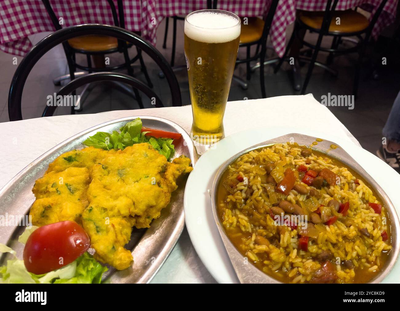 Plat traditionnel de poisson de morue salé appelé Pataniscas de Bacalhau servi avec du riz aux haricots dans un restaurant populaire de Lisbonne. Banque D'Images