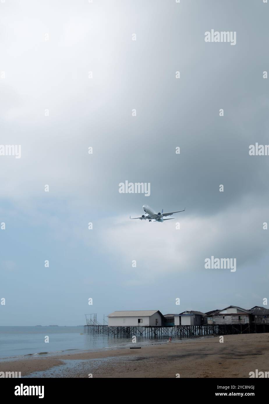 L'avion commercial Garuda Indonesia vole bas au-dessus de la plage de Balikpapan pour se préparer à atterrir Banque D'Images