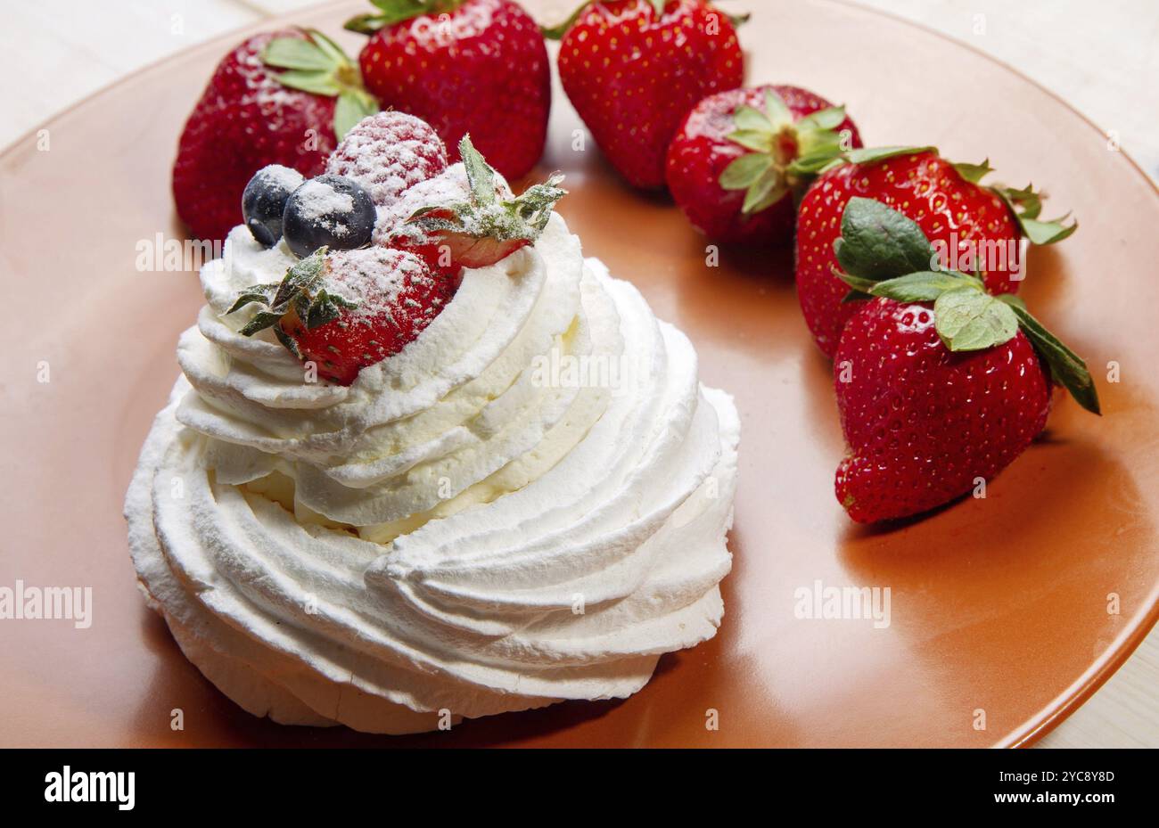 Gâteau meringue décoré de baies sur le dessus sur une assiette brune Banque D'Images