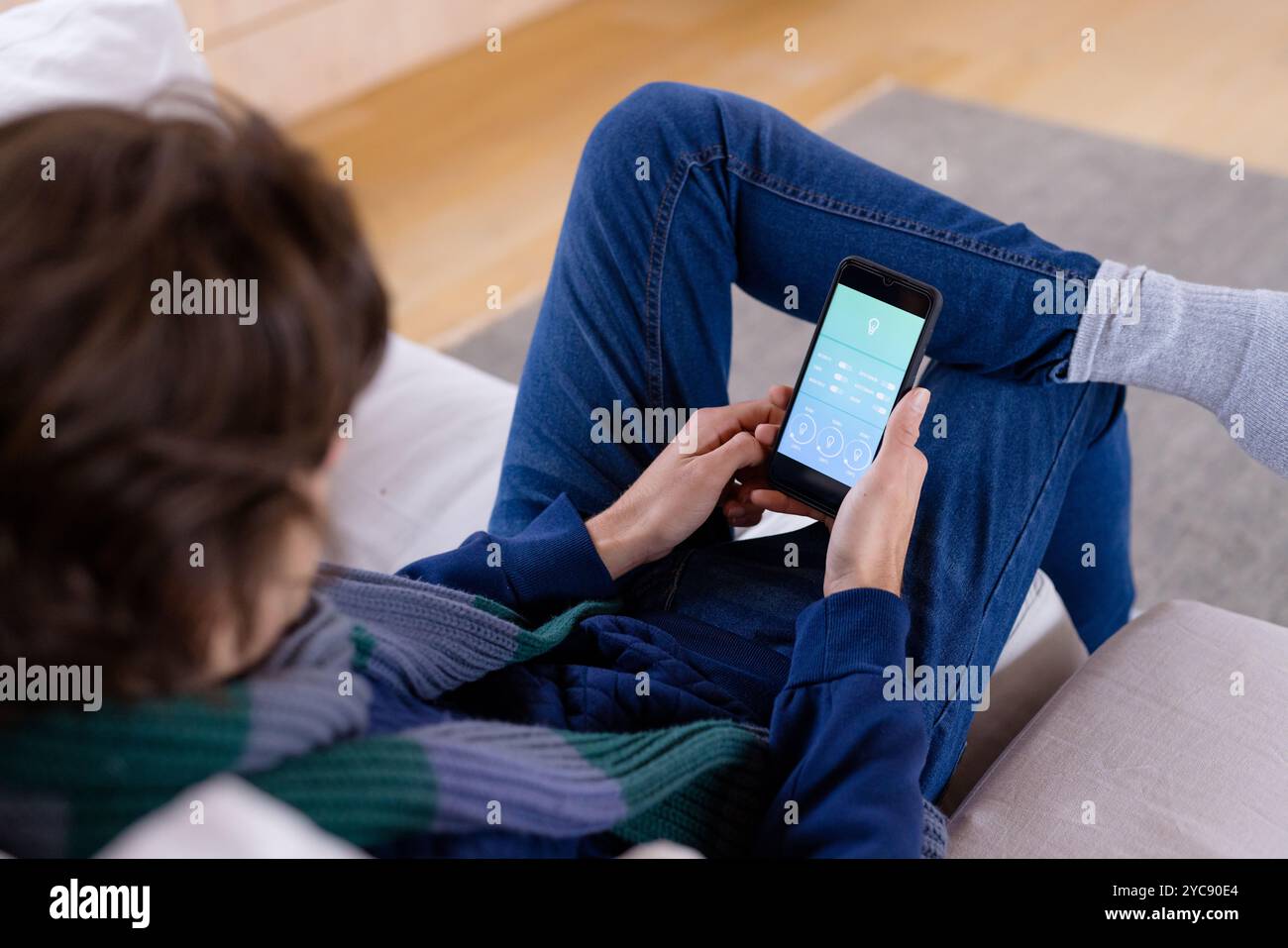 Détente à la maison, personne utilisant l'application smartphone pour le contrôle intelligent de la maison Banque D'Images