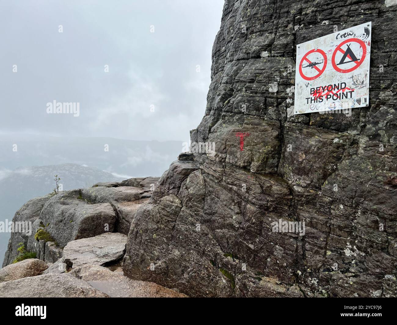 Un panneau 'No Camping' et 'No drones' placé sur un sentier rocheux dans un environnement naturel et montagneux près de Preikestolen en Norvège pour préserver le natur Banque D'Images