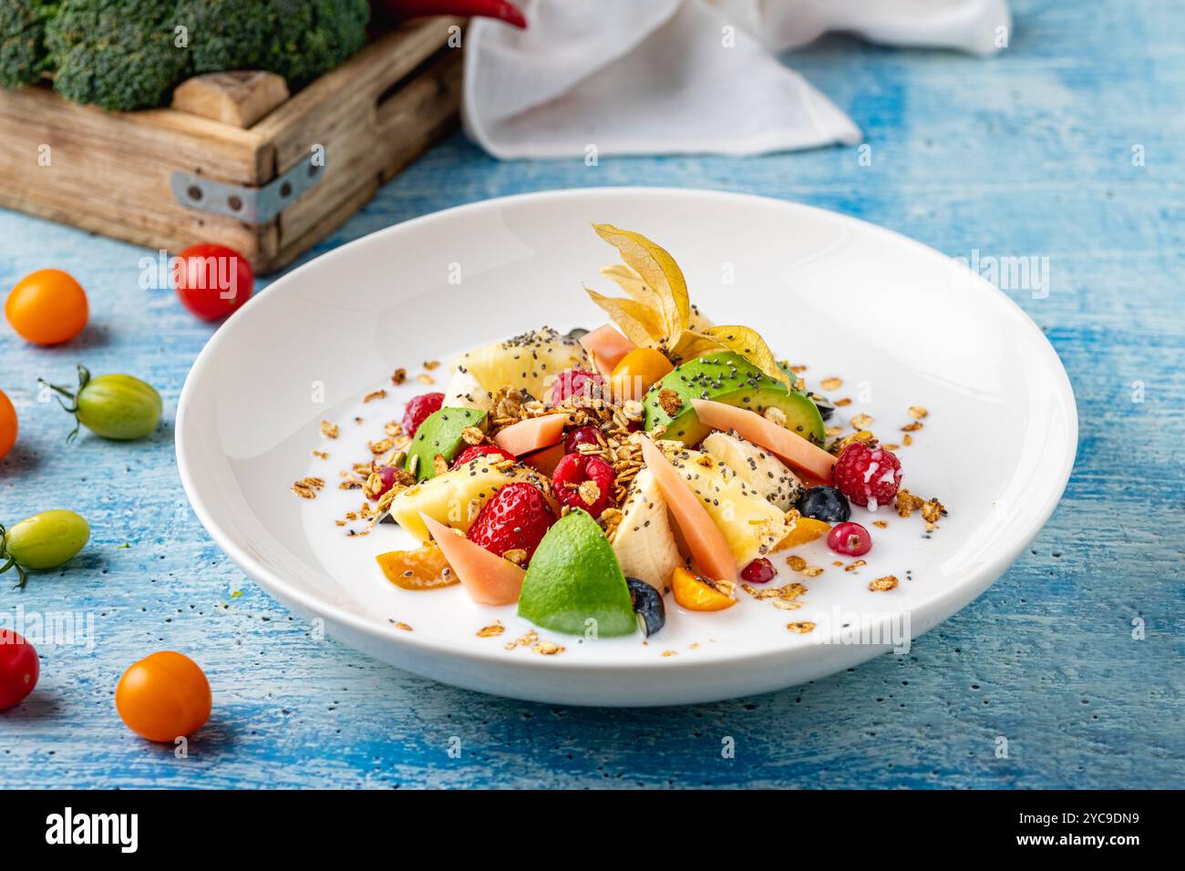 Salade de fruits mélangée avec des fruits tels que banane, fraise et ananas sur une assiette en porcelaine blanche Banque D'Images