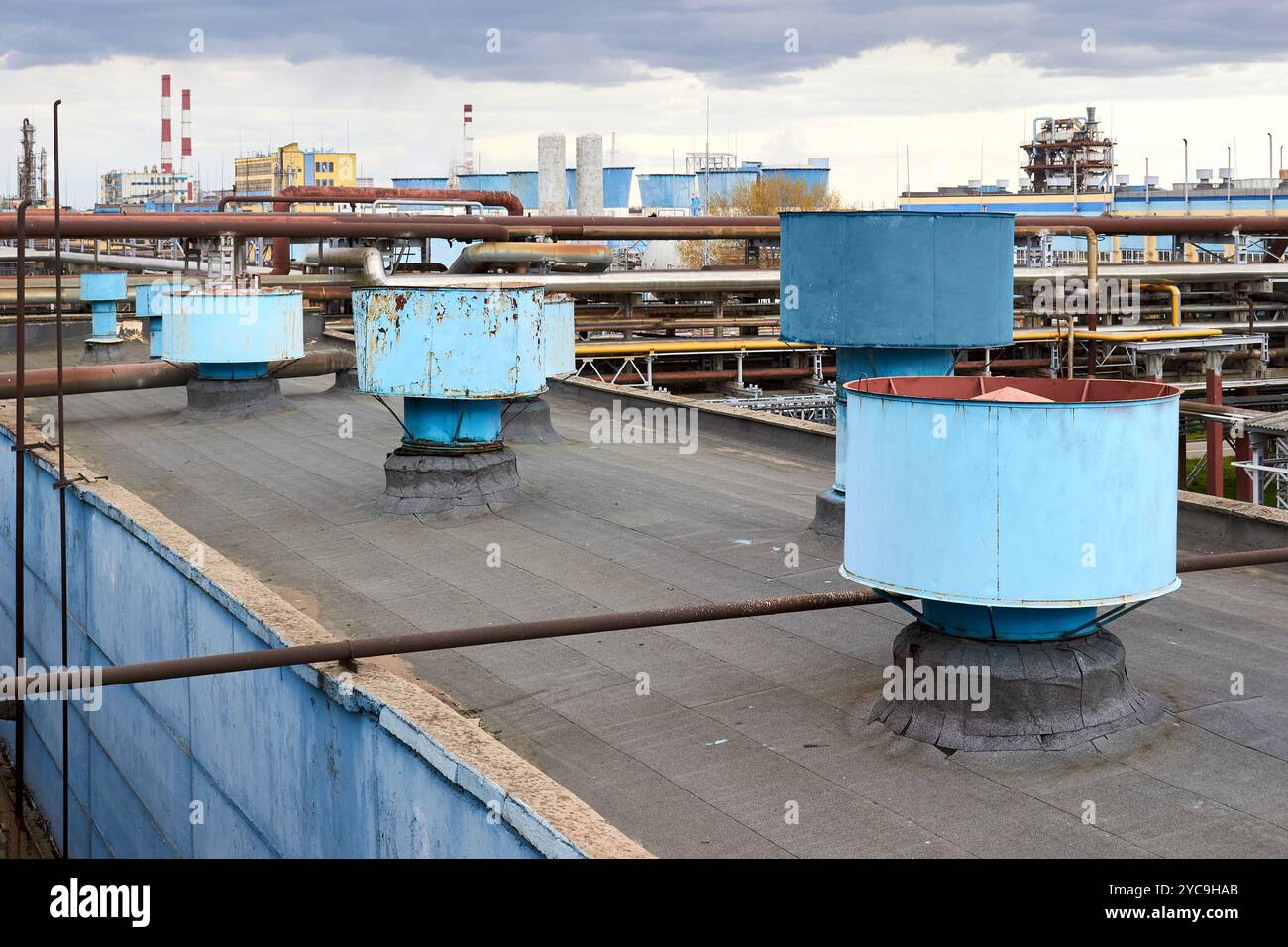 Système de ventilateur de ventilation d'échappement de toit d'air d'un grand bâtiment de production d'atelier pétrochimique industriel. Cheminées à capuchon et conduits en rangée sur le toit Banque D'Images