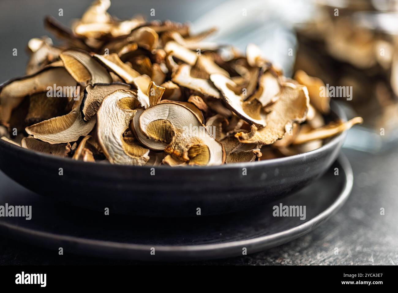 Champignons porcini séchés. Boletus tranché sur une plaque sur une table noire. Banque D'Images