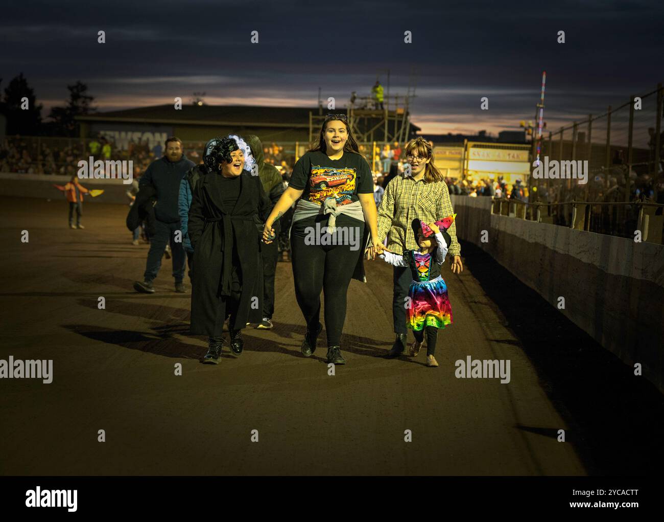 Des membres du public, y compris des enfants, marchent sur la piste pendant la SOIRÉE DE CARNAVAL D'HALLOWEEN à Trackstar Racing, Kings Lynn, Norfolk, Royaume-Uni Banque D'Images