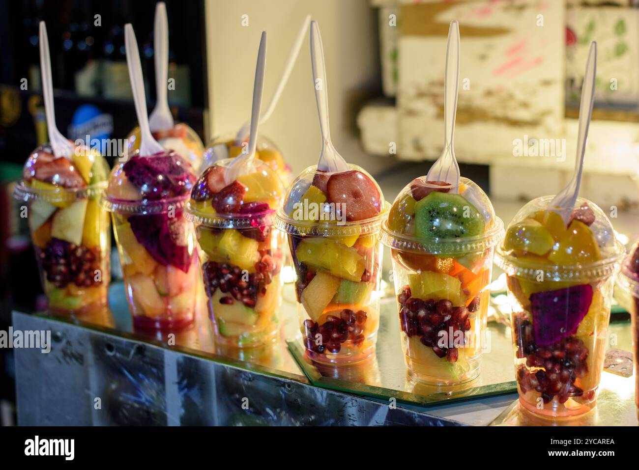 Cuillères et tasses en plastique remplies d'un mélange de fruits fraîchement coupés pour les mélanger dans des milk-shakes et smoothies. Banque D'Images