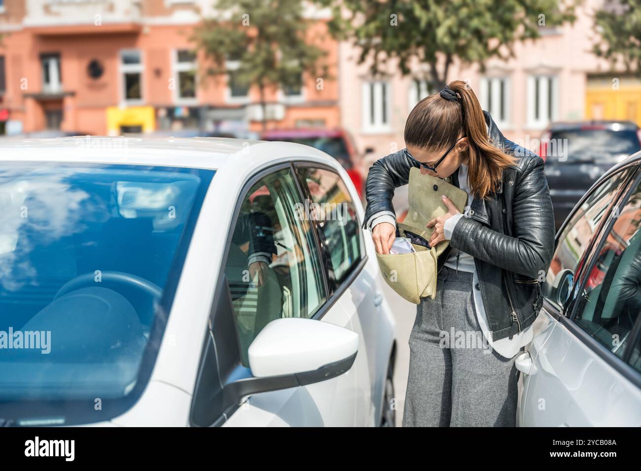 Jeune femme d'affaires nerveuse à la recherche de clés de voiture dans son sac à main debout près du véhicule a perdu la clé de la porte d'entrée tandis que le système de capteur sans clé est hors o Banque D'Images