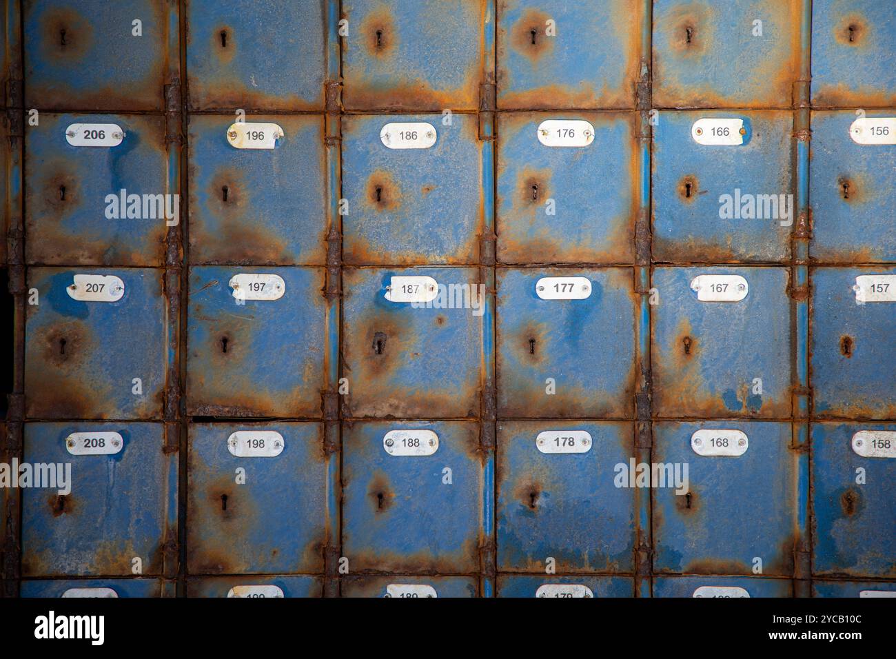 Quatre rangées de vieilles boîtes aux lettres bleues rouillées dans un bureau de poste abandonné. Banque D'Images