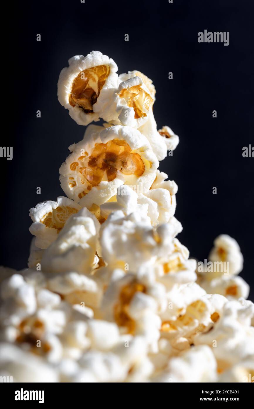 Plan macro d'une collation nostalgique, mettant en valeur du pop-corn beurre sur un fond sombre, rappelant des soirées cinéma vintage. Banque D'Images