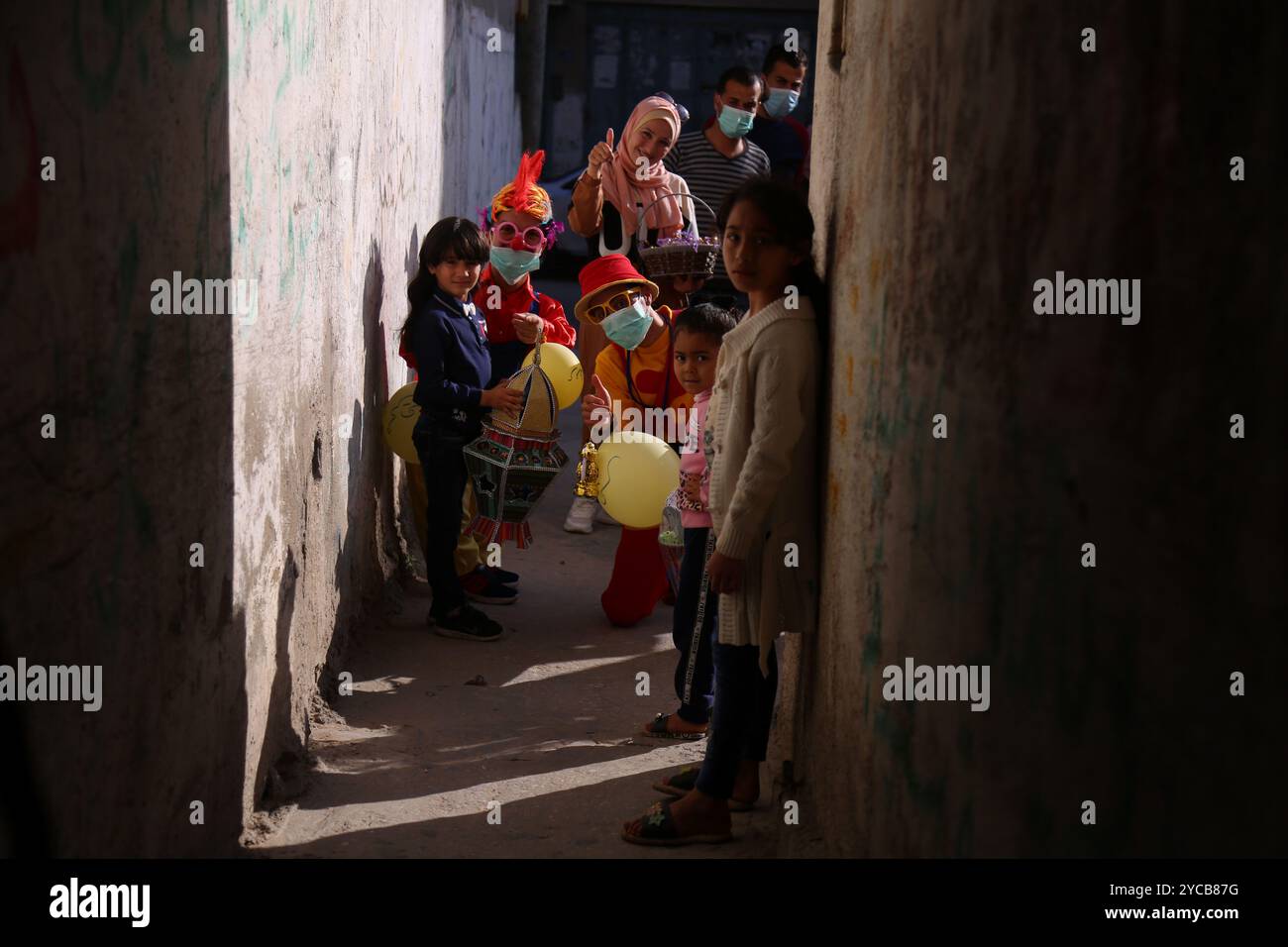 Gaza, Palestine. 24 avril 2020. Deux clowns portant des masques de protection divertissent les enfants et distribuent des bonbons et des lanternes dans le camp de réfugiés de Nuiserat à Gaza au début du mois du Ramadan. Le chômage élevé et la pauvreté caractérisent la situation de nombreux résidents du camp, déjà touchés par le blocus israélien imposé à l'enclave palestinienne depuis 2007. Avec la pandémie de coronavirus de cette année et les mesures préventives, le Ramadan va être différent, avec une situation économique encore plus difficile et une interdiction de se rassembler pour les repas, les prières et les célébrations communautaires Banque D'Images