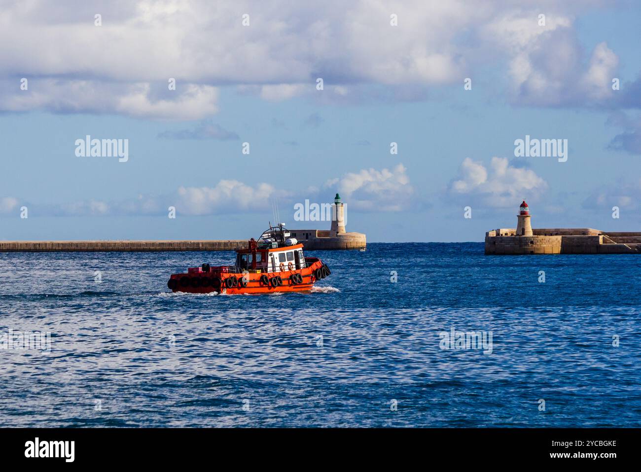 Red Tugboat naviguant dans l'océan bleu près de Stone Breakwater Banque D'Images