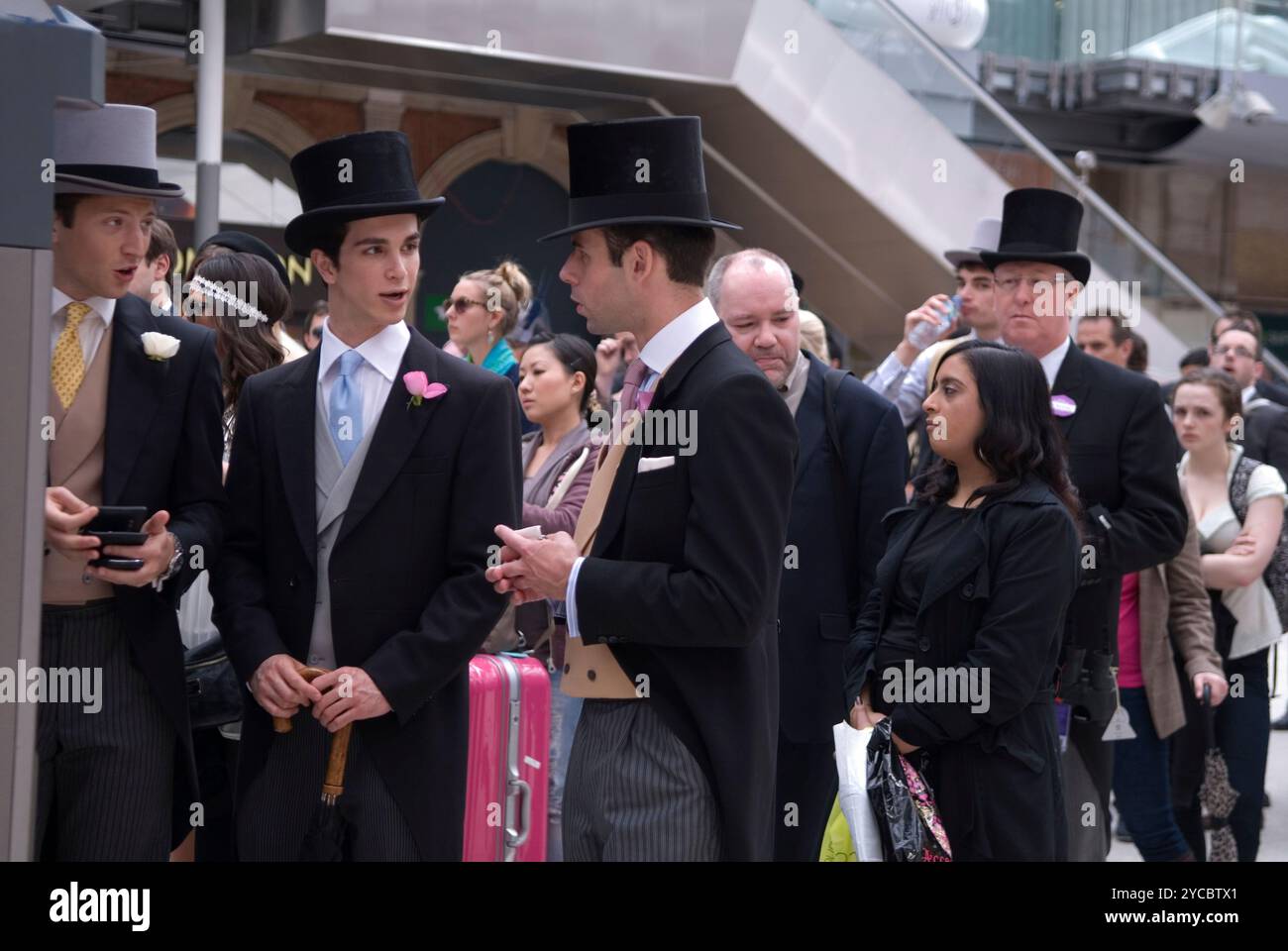 Attente en ligne pour acheter un billet de train à un distributeur automatique. Groupe de jeunes hommes qui vont à Royal Ascot portant des chapeaux et des manteaux de queue de code vestimentaire. Ils semblent différents des gens ordinaires qui font la queue. Gare de Waterloo Londres, Angleterre 22 juin 2012 2010s UK HOMER SYKES Banque D'Images
