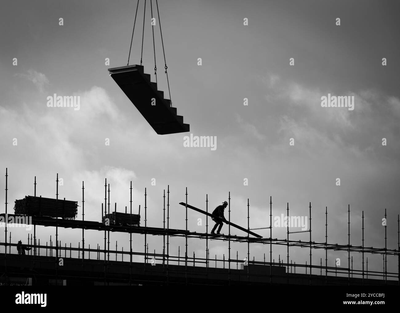 Scène du chantier de construction d'un immeuble moderne de grande hauteur avec ouvrier de construction sur échafaudage en silhouette Banque D'Images