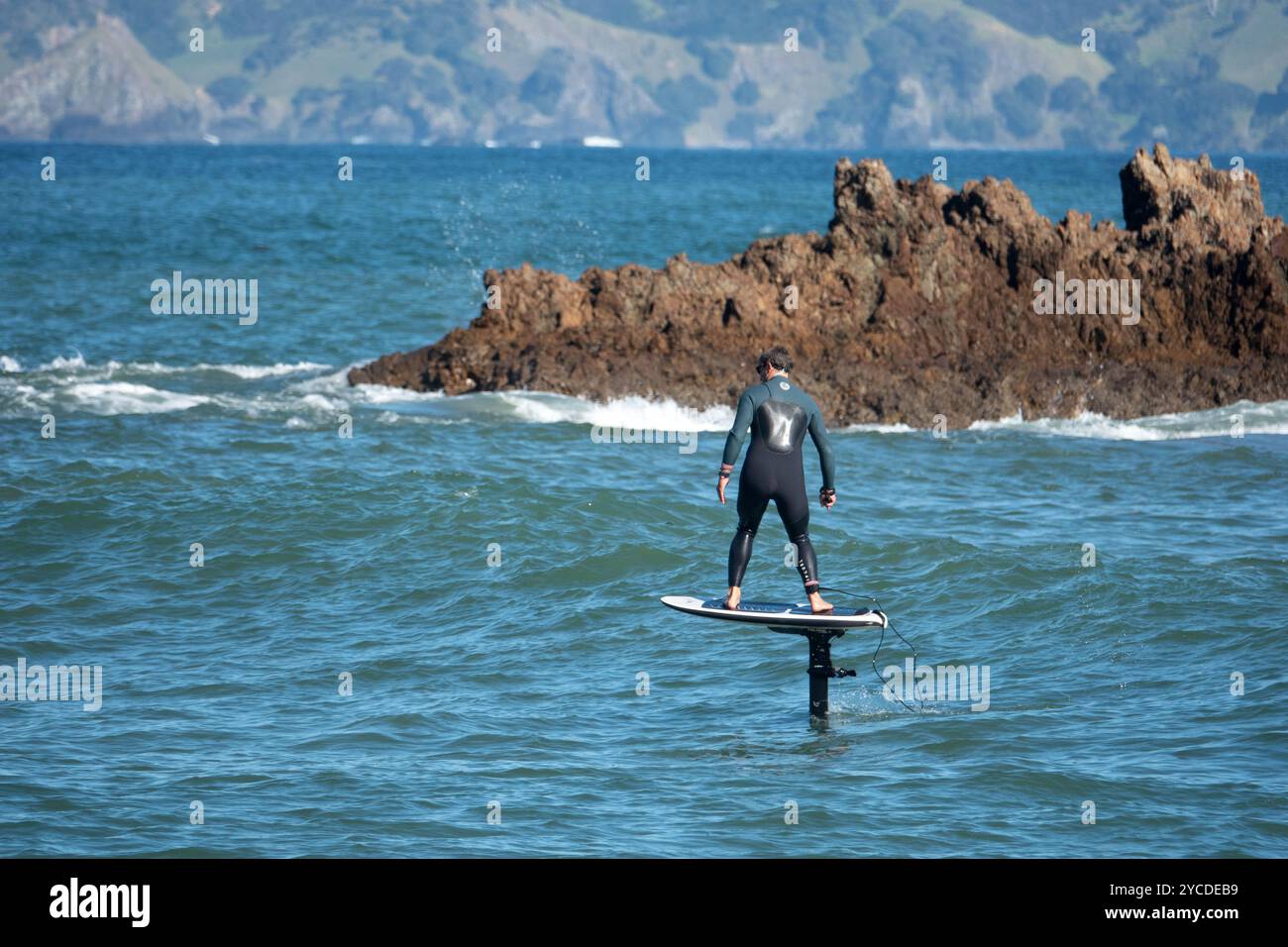 Homme surfant sur une vague sur une planche efoil à Tauranga Bay, Northland, Nouvelle-Zélande Banque D'Images