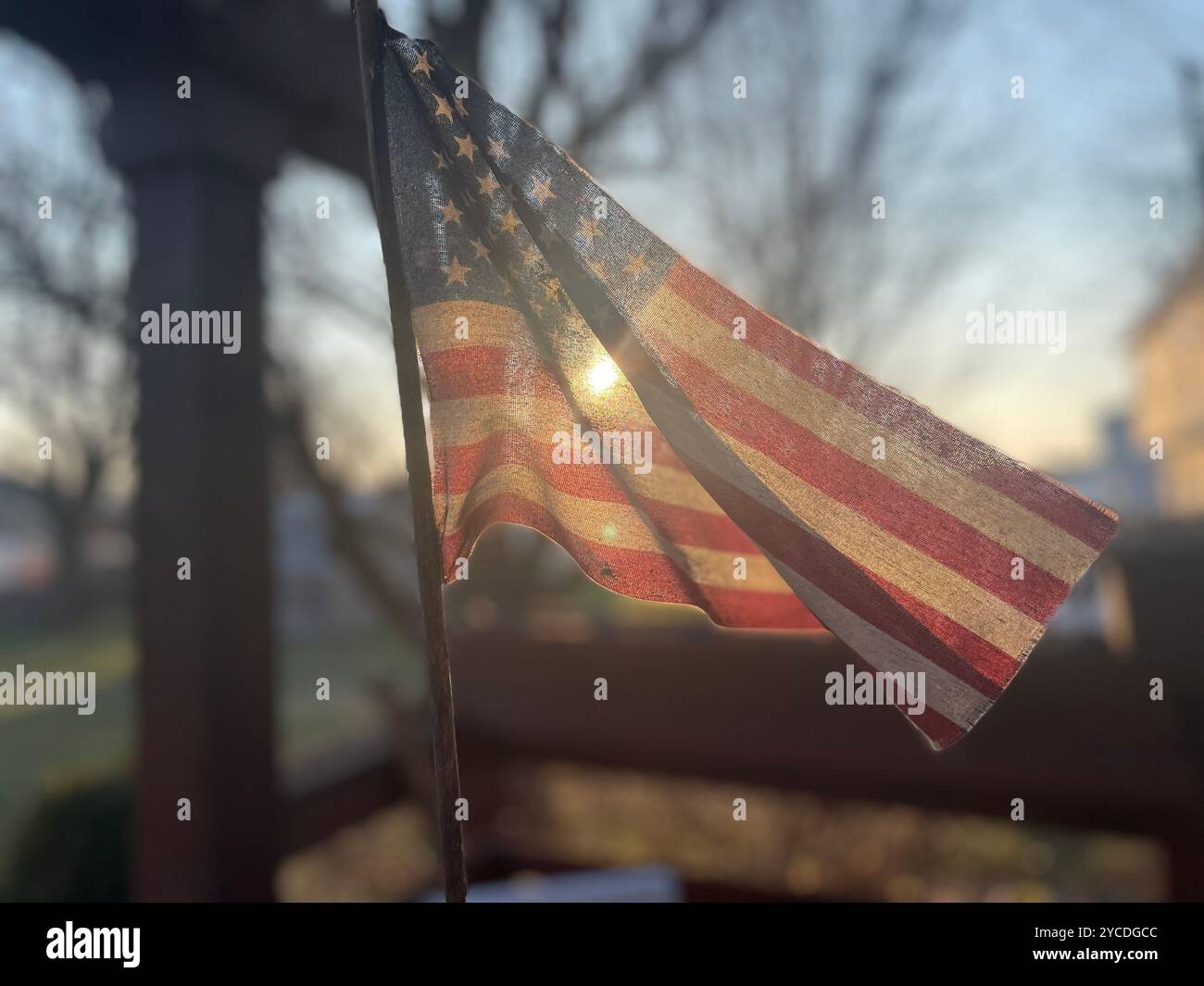 Drapeau américain rétroéclairé ondulant doucement avec des rayons de soleil qui brillent à travers. Scène extérieure patriotique capturée pendant l'heure dorée en mode flou. - Image de stock capturée avec un smartphone